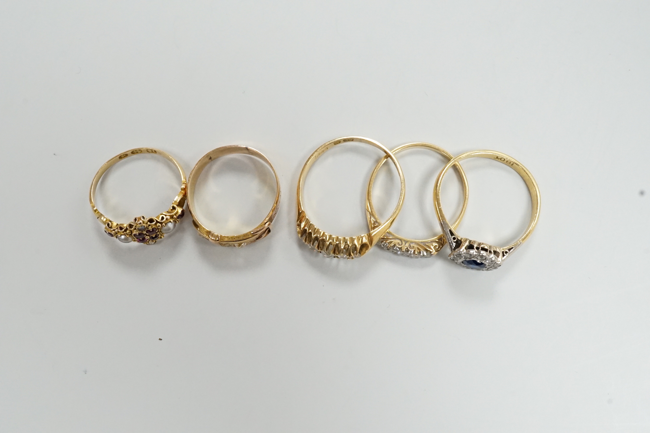 A Victorian 18ct gold and gem set dress ring, size I, three other 18ct and gem set rings and a yellow metal and diamond set buckle ring, gross weight 13.3 grams.